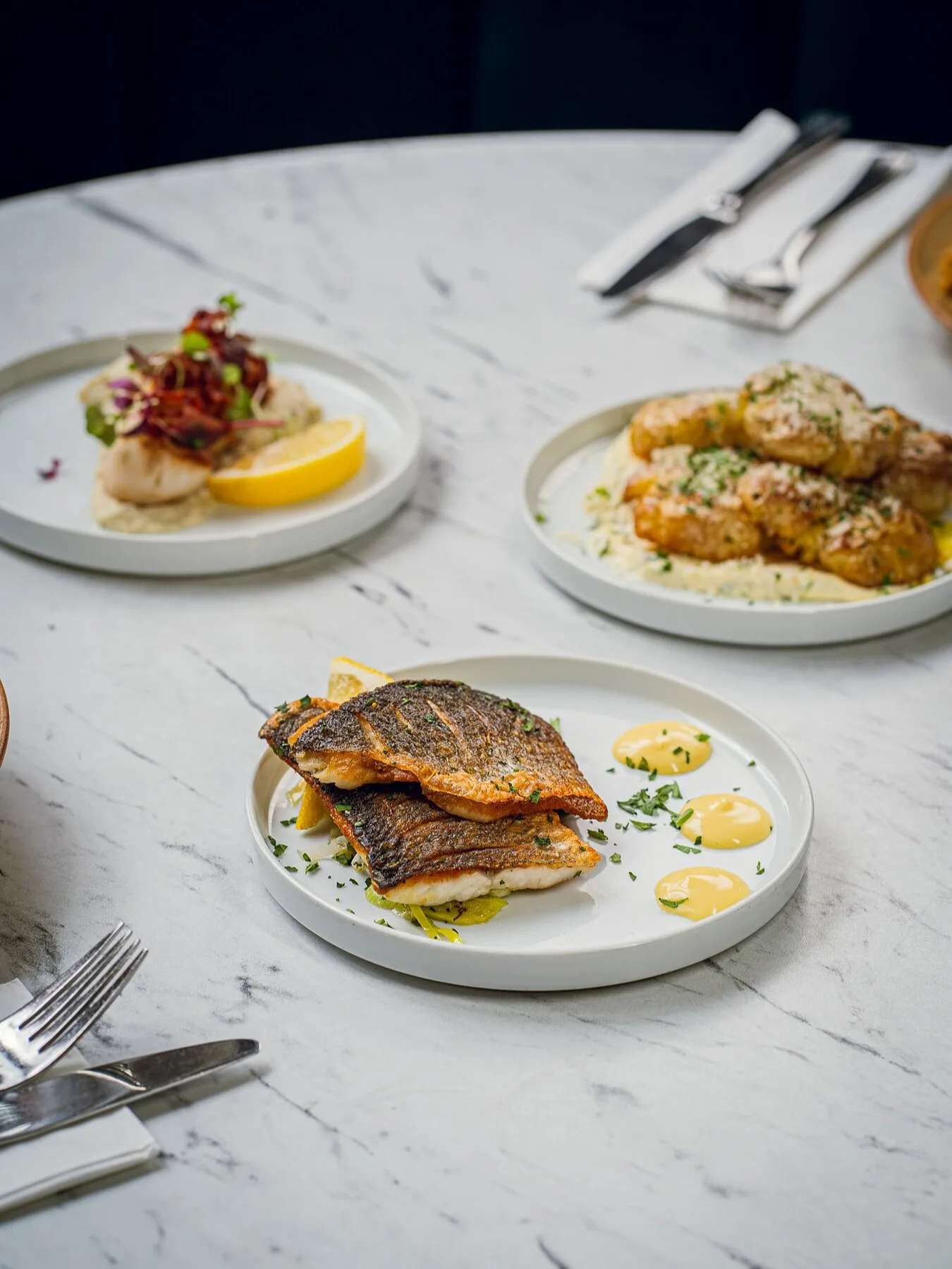Sea bass, scallops, and sides on marble
